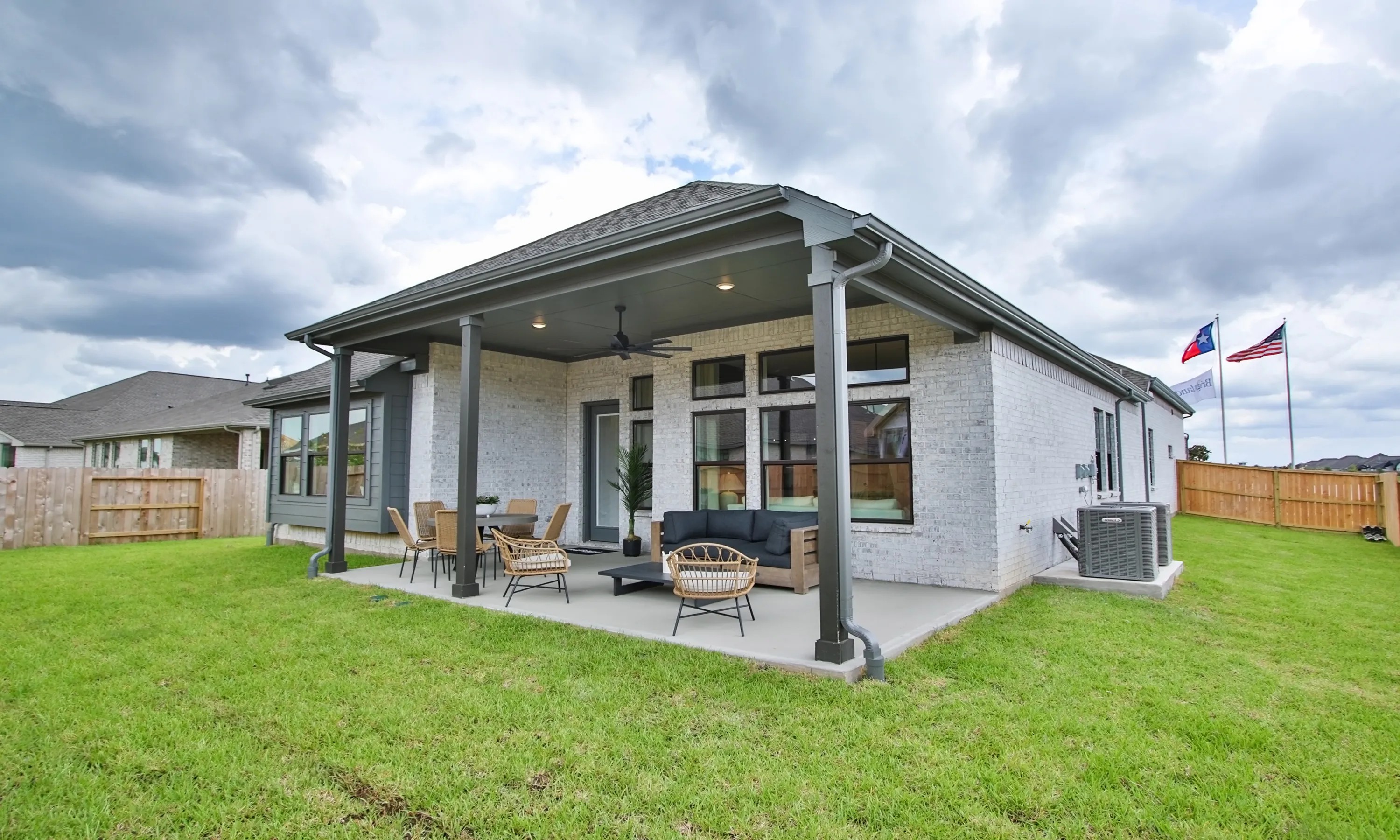 Coastal Point Texas Home Patio with Elegant Design Elegant patio with ceiling fans, brick exterior, and manicured lawn in Coastal Point, Texas suburb.