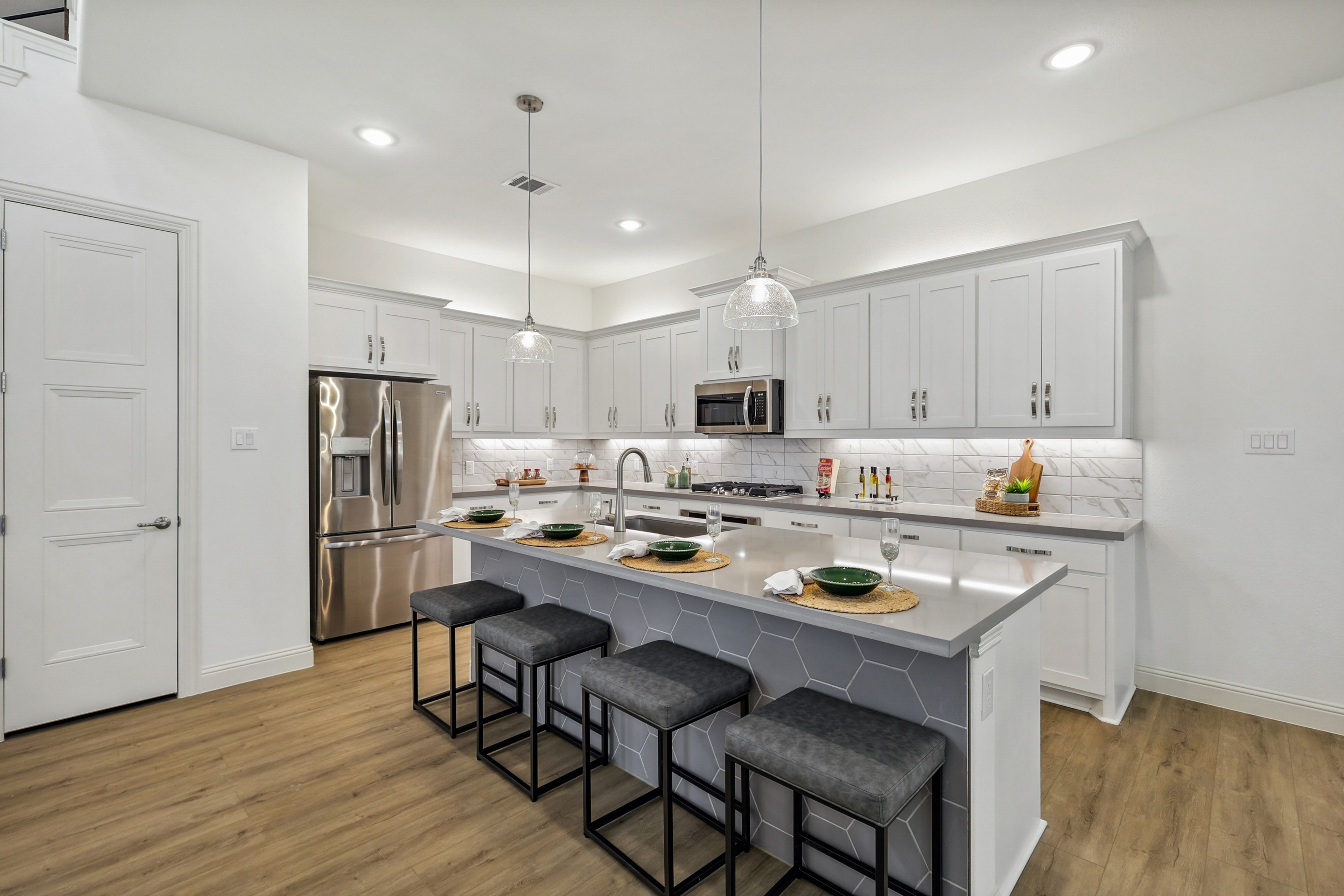 Contemporary Kitchen Design with Island in Solterra, Texas Modern kitchen with pendant lights, island seating, white cabinets, stainless steel appliances. Solterra, Texas.