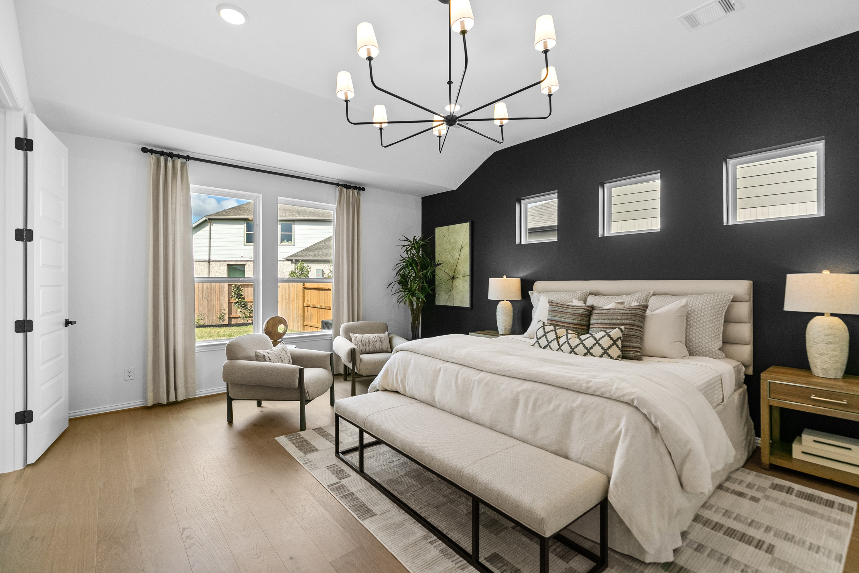 Luxurious Bedroom with Black Accent Wall in River Ranch Elegant bedroom with black accent wall, chandelier, large windows. Luxurious design in River Ranch community.