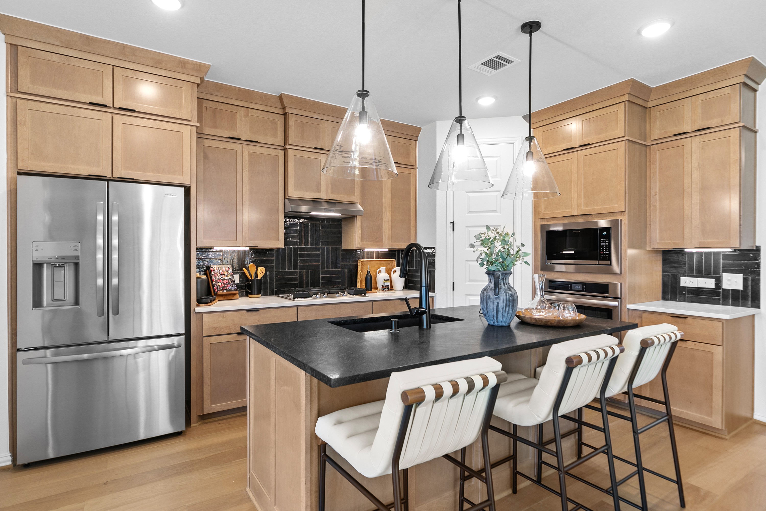 Elegant Kitchen with Wooden Cabinets in River Ranch Community Modern kitchen with wooden cabinets, black island, and pendant lights in River Ranch community.