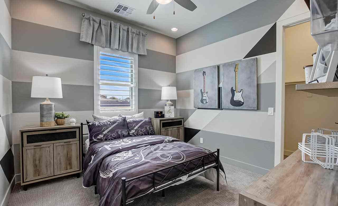 Stylish Bedroom with Guitar Art in Mirada Crossing Home Modern bedroom with striped walls, guitar art, cozy furnishings, in Mirada Crossing community.