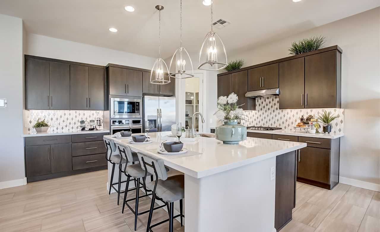 Mirada Crossing Luxury Kitchen with Island and Pendant Lights Modern kitchen at Mirada Crossing; dark cabinets, island, pendant lights, stainless appliances, tile backsplash.