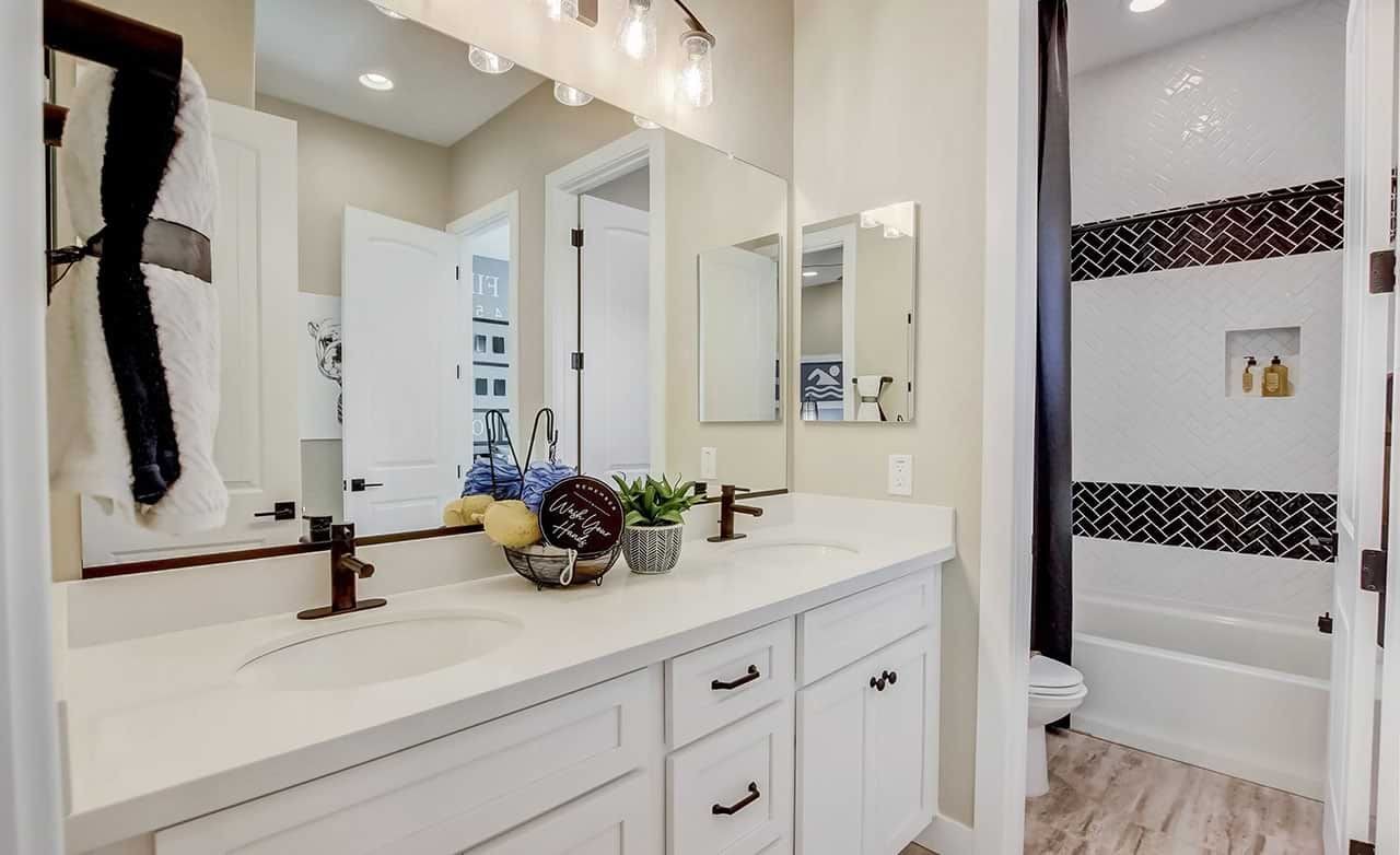 Elegant Bathroom in Mirada Crossing with Double Vanity and Tile Accents Luxury bathroom in Mirada Crossing with double vanity, white cabinets, decorative tile, modern fixtures.