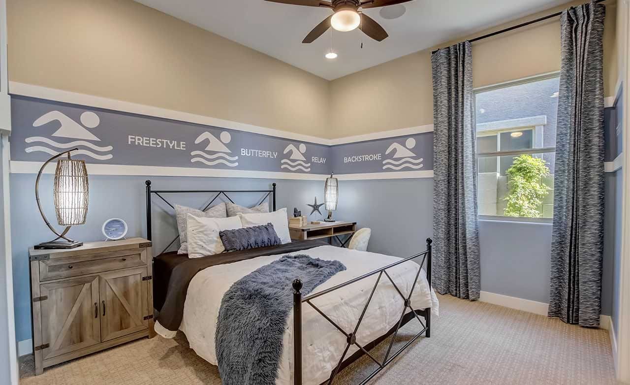 Swim-Themed Bedroom at Mirada Crossing with Wrought Iron Bed Bedroom with swim-themed decor, wrought iron bed, ceiling fan, and large window. Mirada Crossing community.