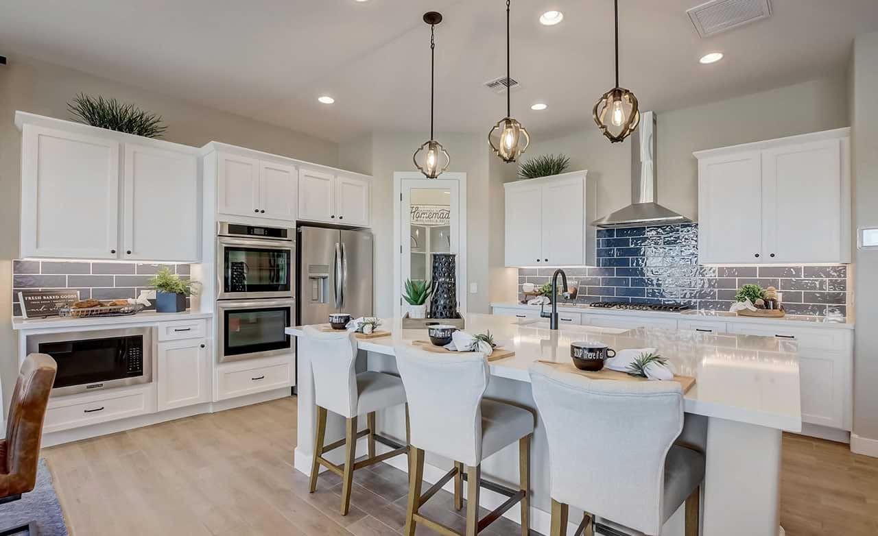 Modern White Kitchen in Mirada Crossing with Blue Tile Backsplash Modern kitchen with white cabinets, blue tile backsplash, and island seating. Located in Mirada Crossing, highlights elegance.