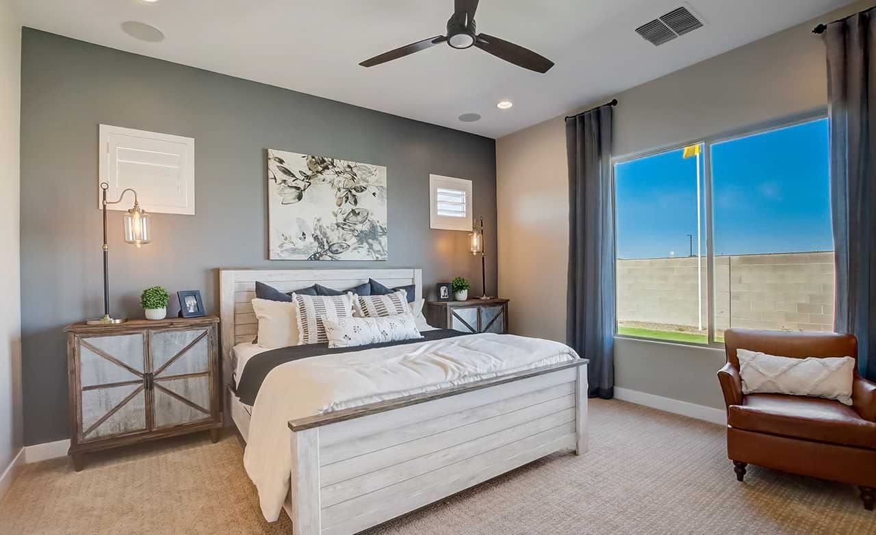 Elegant Bedroom Design in Mirada Crossing with Gray Accent Wall Elegant bedroom with gray accent wall, modern ceiling fan, large window. Mirada Crossing, contemporary furniture.
